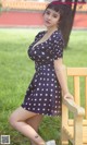 A woman in a blue dress sitting on a wooden bench.