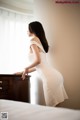 A woman in a white dress standing on a bed.