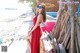 A woman in a red dress sitting on a wooden bench.