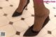 A close up of a woman's feet in high heels on a tiled floor.