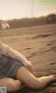 A woman laying on the beach with her legs crossed.