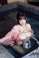 A woman in a kimono is tied up in a bathtub.