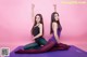 A couple of women sitting on top of a purple mat.