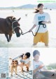 A woman is petting a horse and a dog on the beach.