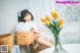 A woman sitting on a chair holding a basket of flowers.