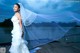 A woman in a wedding dress standing on a dock.